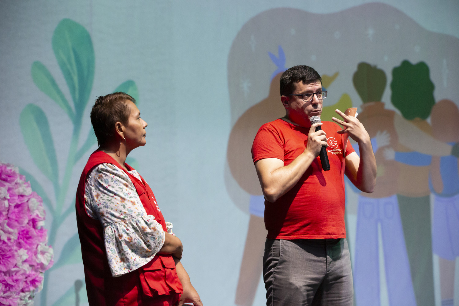 Un hombre con micrófono en mano junto a mujer escuchando