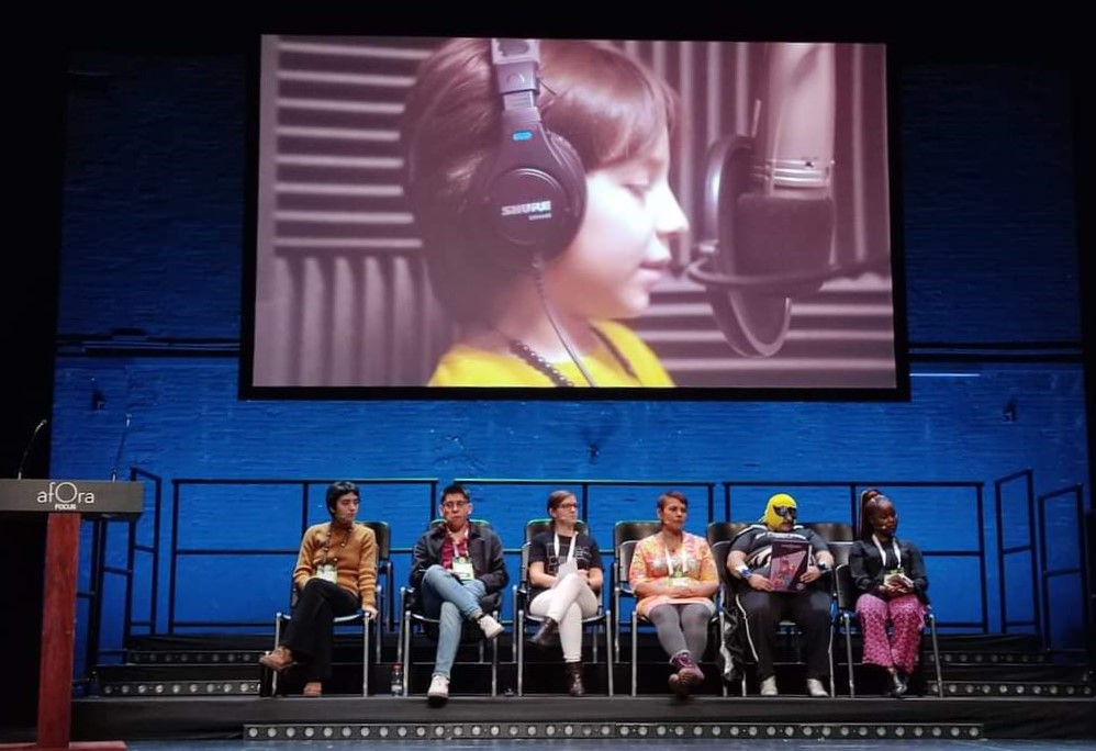 Grupo de personas en el escenario con pantalla de fondo