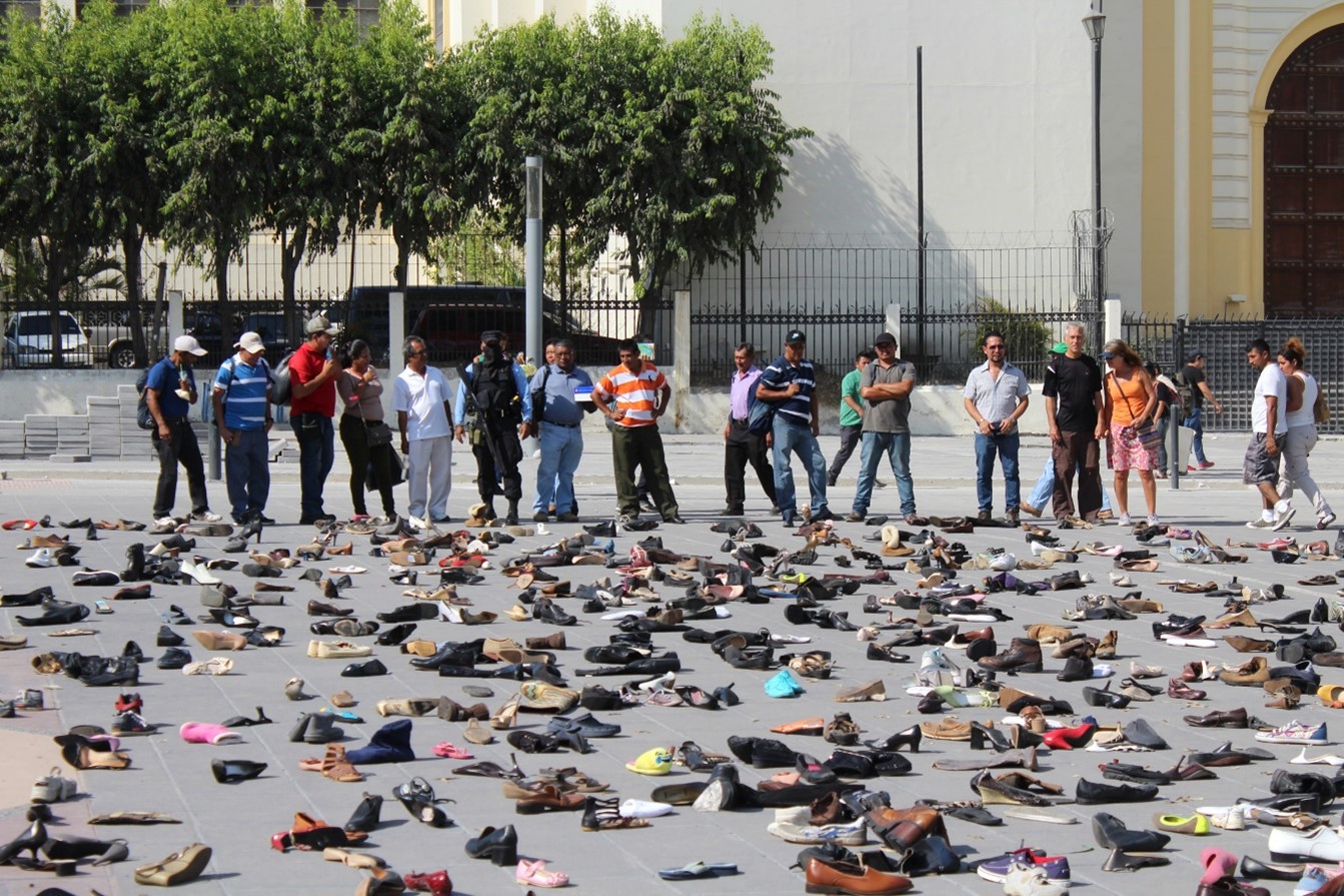 Calle con grupo de personas mirando zapatos tirados en el suelo